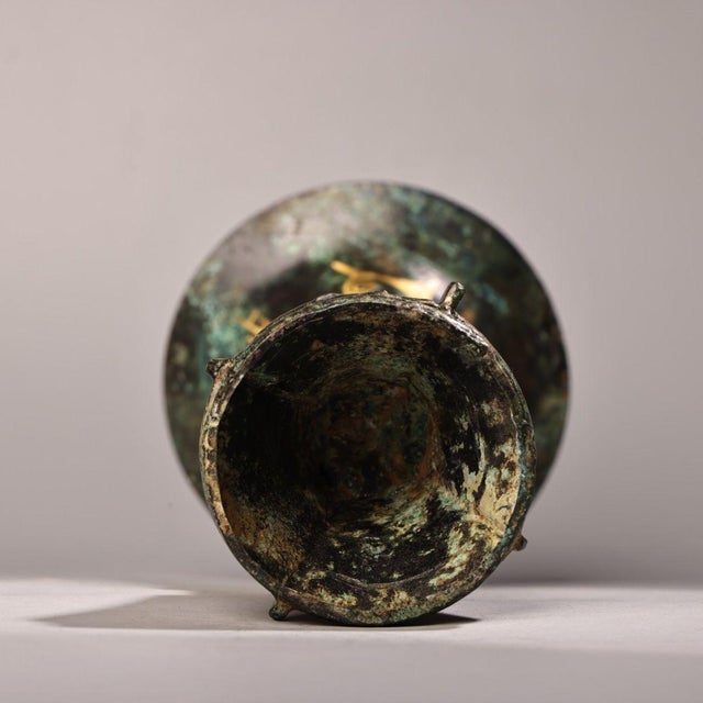 Tall elegant archaic bronze Gu vase with wide flared mouth and tiered pedestal base. Bright gold inlay forms flowing...