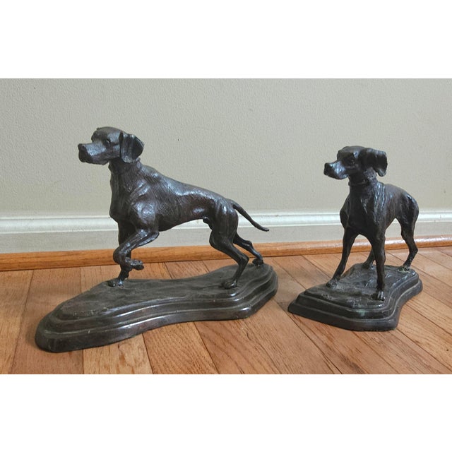 A Pair of Early 20 Century Patinated Bronze male and female Hounds. Larger measures 13" in width, 5" in depth and 8.5"...