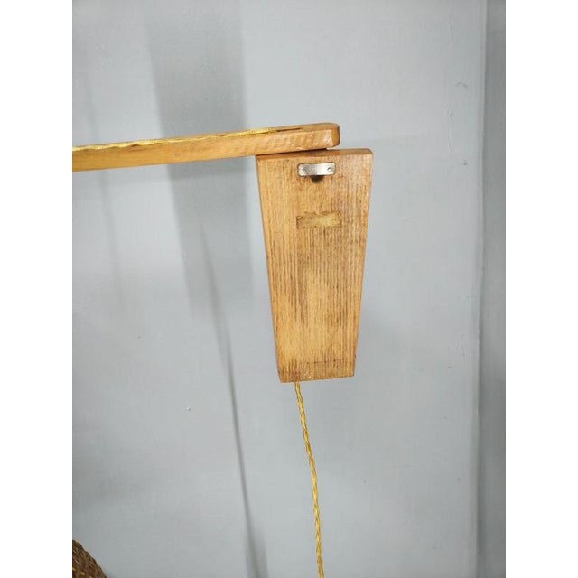 Distinctive czechoslovak swing arm wall lamp dating from the 1960s, crafted from wood and woven rattan. The design...