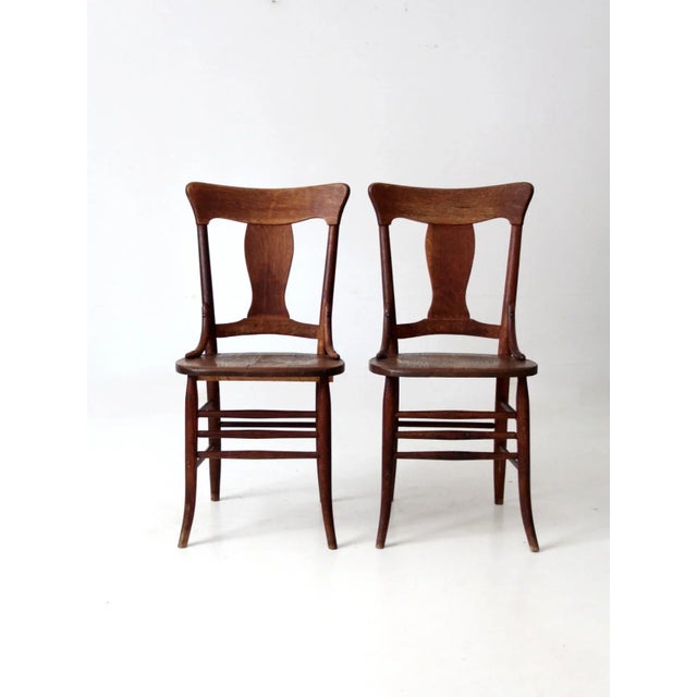 This is a pair of antique Murphy Chair Company chairs. The wooden dining chairs feature "fiddle" shaped back splats with...