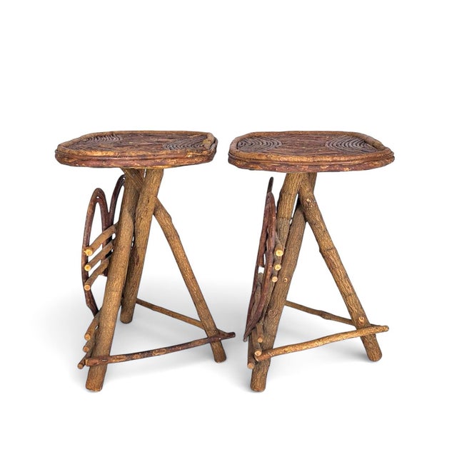 A pair of Adirondack-style side tables featuring intricate bent-twig joinery and a warm, natural patina. Each table is...