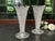 A matching pair of vintage clear glass trumpet vases featuring intricate pressed-glass patterns, scalloped rims, and...