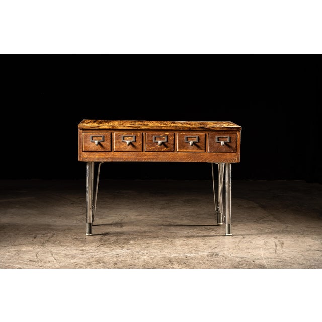 This vintage card catalog features a set of mid century legs and five pull drawers. Each of the five drawers have...