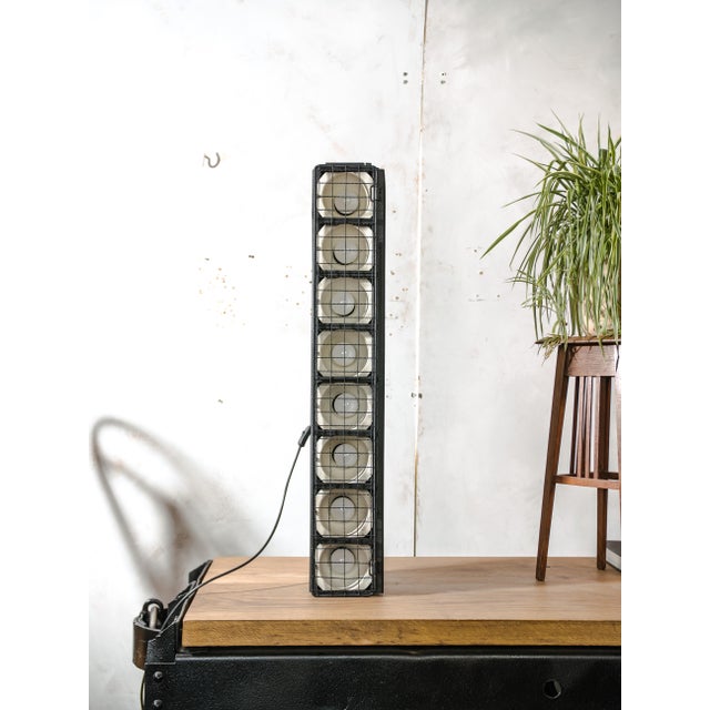 A long stage batten by siemens with eight lamp positions, each behind a white reflector cup, and a hinged black wire...
