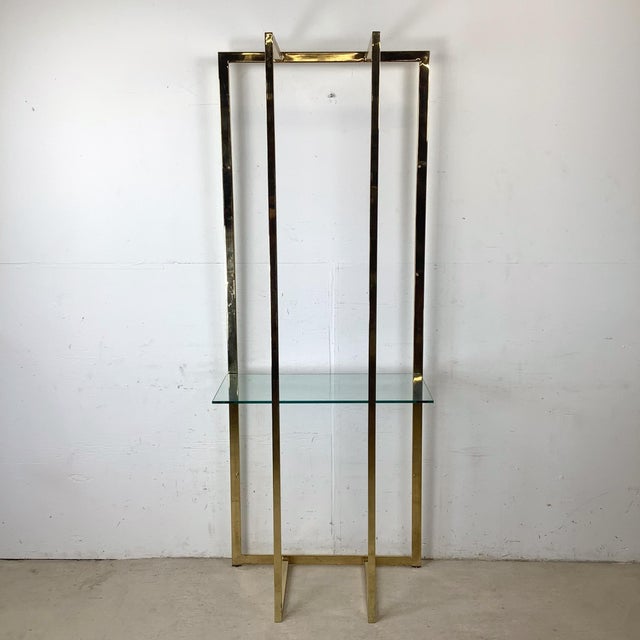This vintage modern étagère features a tall, sculptural brass frame paired with a clear glass shelf, creating a refined...