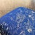 The surface carries a deep navy ground overlaid with an abstract gold metallic texture, the pattern spreading unevenly...