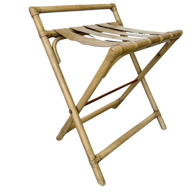 A mid-century folding luggage rack featuring a sturdy bent rattan frame paired with thick, supple tan vinyl / faux leather...