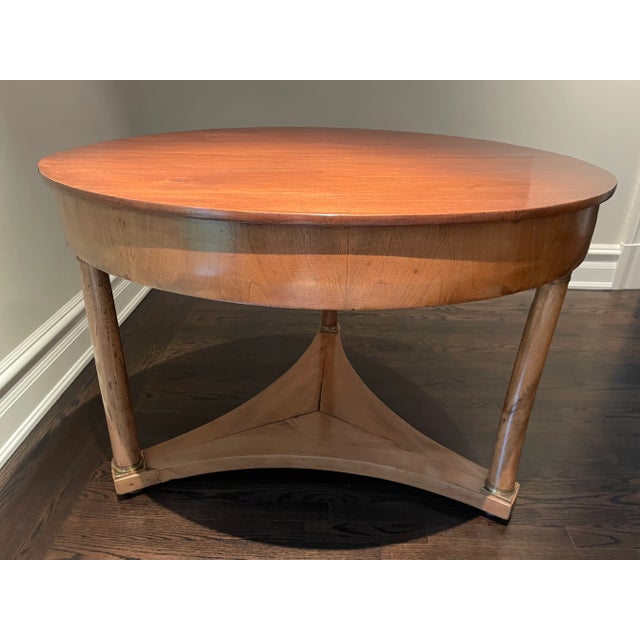 Northern Italian Empire Period Fruitwood center table. The rounded top sits over an apron, raised on three columnar legs...