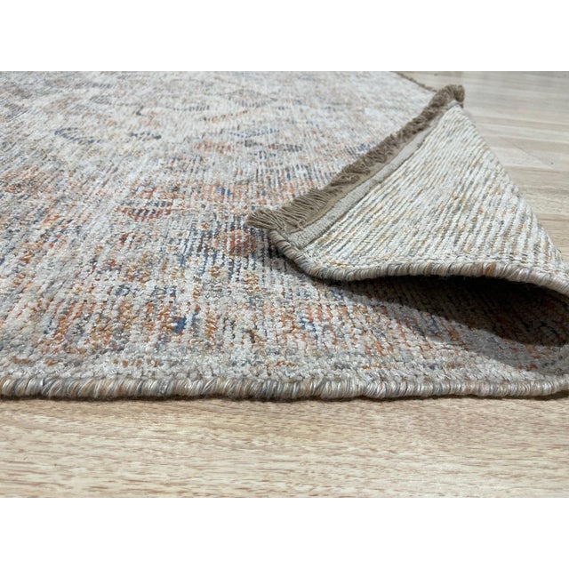 A 6' x 9' hand-knotted wool rug with a softly faded ivory and powder blue field with a classic central medallion and a...
