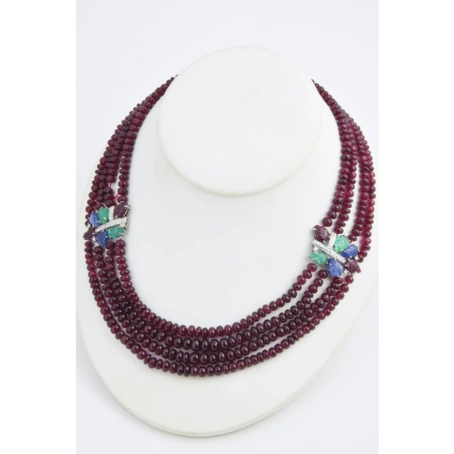 Impressive contemporary necklace containing four strands of ruby beads accented with two - 18k white gold tutti frutti...