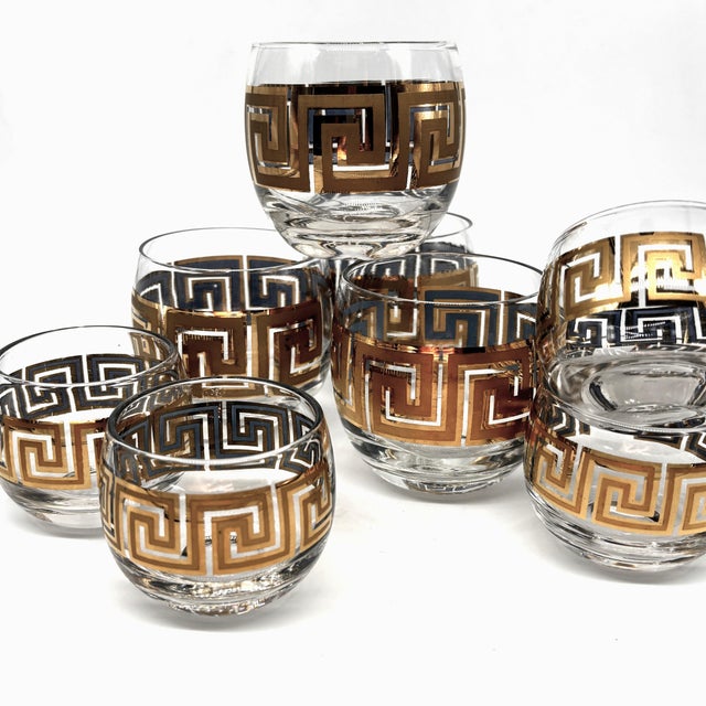 A sophisticated set of eight vintage bar glasses featuring a classic 22-karat gold Greek Key motif on clear glass. This...