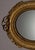 Elegant oval wall mirror in a finely carved and gilt wooden frame, decorated with engraved foliate and classical motifs...