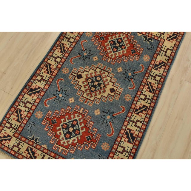 A tribal Caucasian Kazak rug hand-knotted with fine wool on a cotton foundation. This rug features geometric medallions...