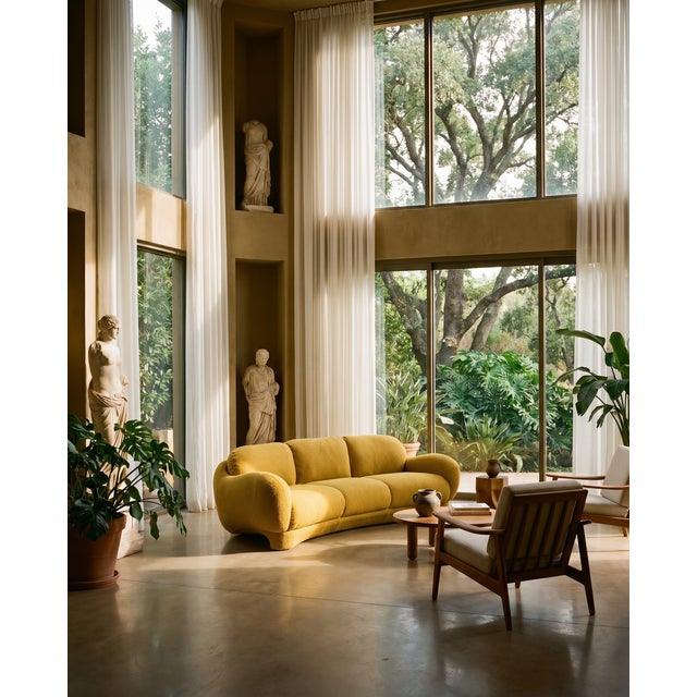 A bold vintage sofa with a soft, sculptural silhouette and a rich ochre bouclé upholstery. The form is low, rounded, and...