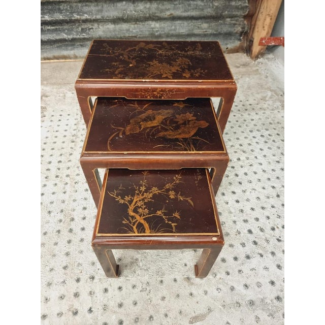 Old set of nesting tables from France from the 1960s. The gold-colored paintings give these wooden nesting tables an...
