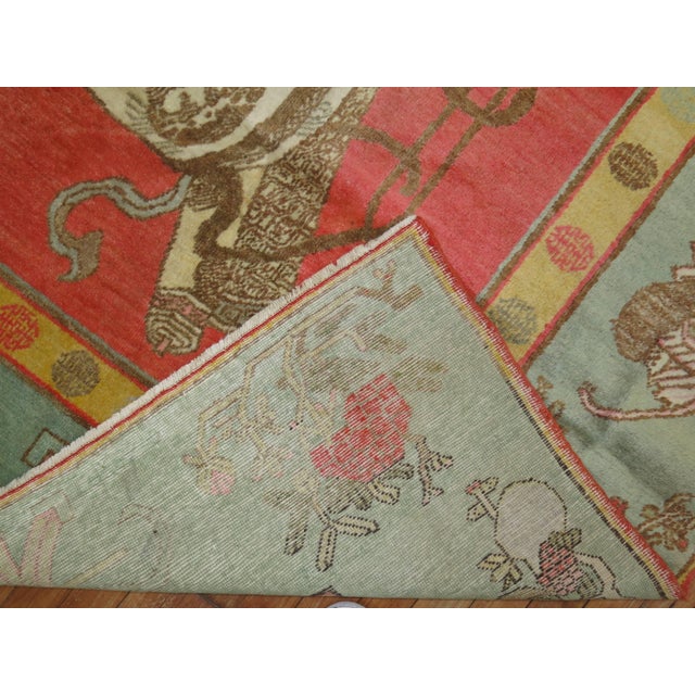 An early 20th century full pile antique Khotan rug featuring a watermelon color field and green border. This piece is not...