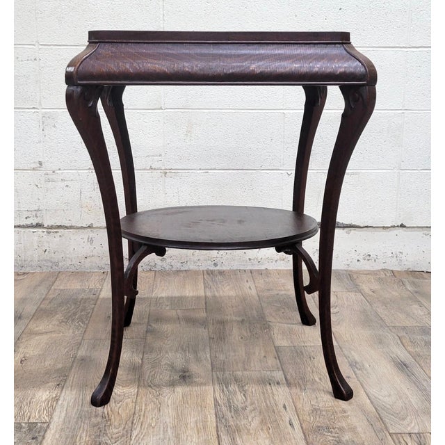 This is a gorgeous antique tiger oak two tier parlor table, lamp table, or plant table. It features cabriole legs, a...