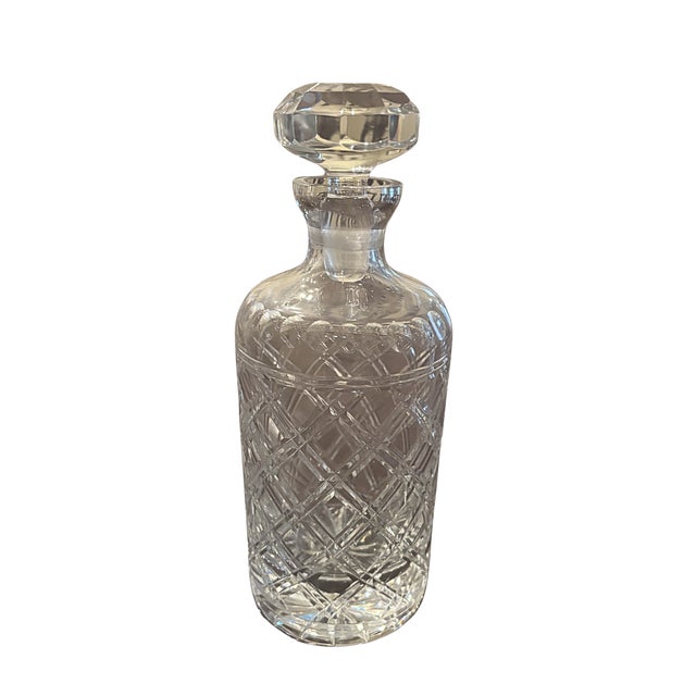 A collected set of five vintage crystal liquor decanters, each featuring a distinctive silhouette, decorative pattern, and...