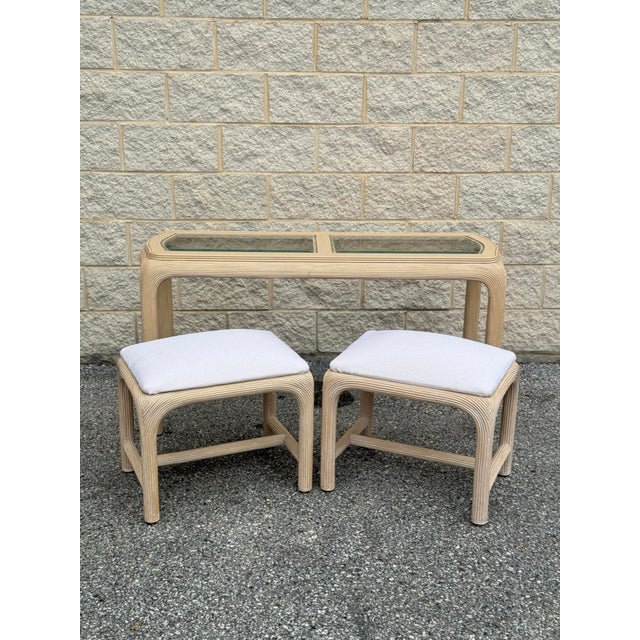 1970s console table in reed-wrapped construction with inset glass top, accompanied by a pair of matching stools. The...