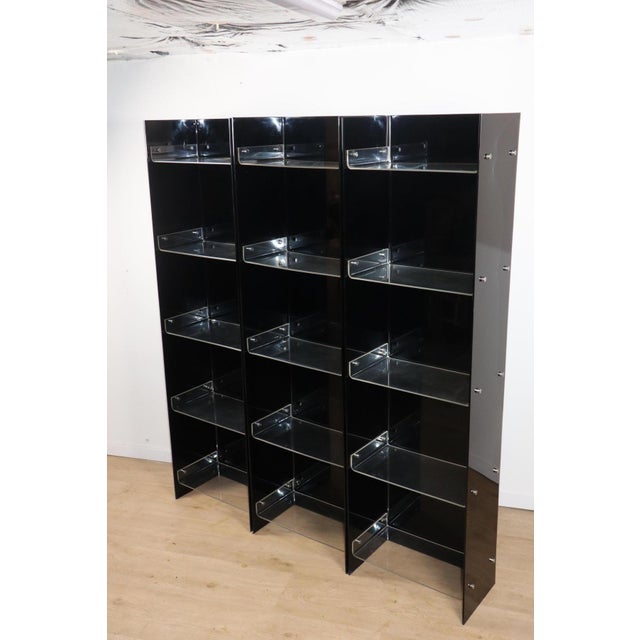 Vintage bookcase composed of three modules in deep black acrylic glass, accented by delicate transparent shelves and...