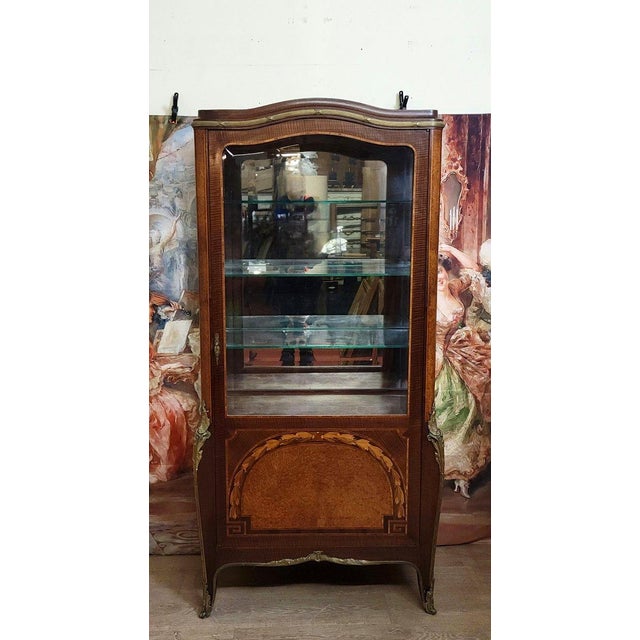 A marquetry display cabinet in fine woods, typical of the louis xv-louis xvi transition style. the front features an...
