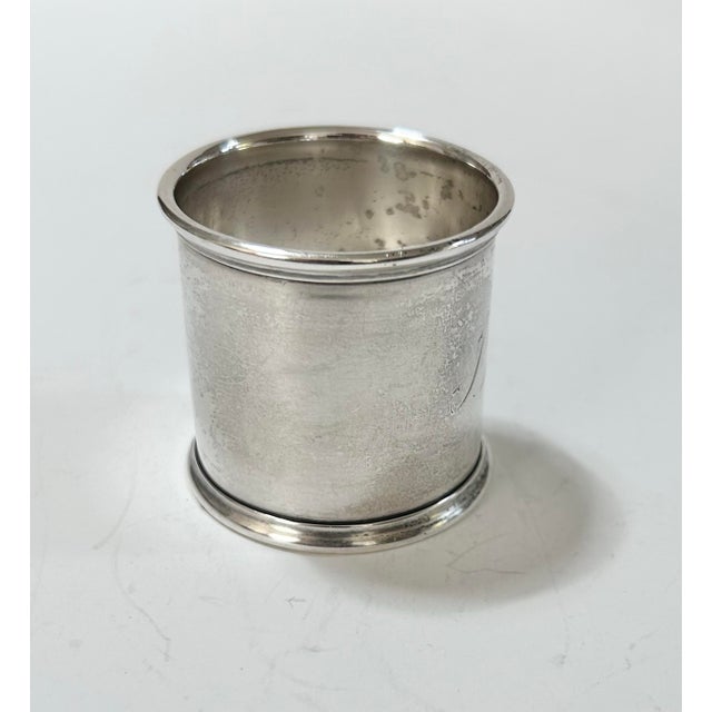 A substantial antique sterling silver napkin ring featuring an elegant engraved script monogram. Its unusually wide band,...