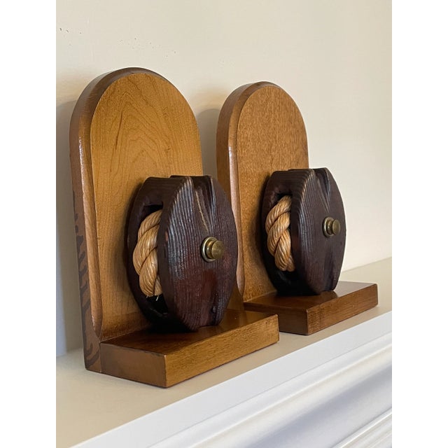 A vintage nautical looking pair of rope pulley and solid wood bookends. Two tone and textured wood are used for base, back...