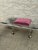 Vintage 1970s vanity stool with a clear lucite frame, brass accents, and pink velvet upholstery. Simple curved legs with...