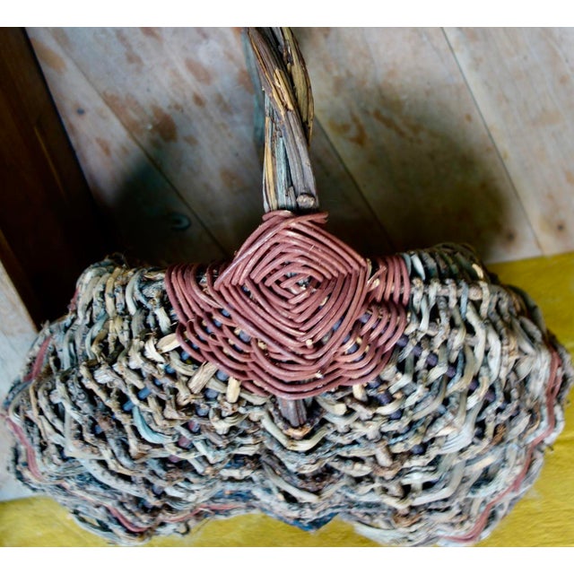 Vintage hand woven buttocks basket created by hand from twigs, including the bent handle. Dyed red reeds form the "God's...