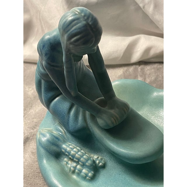 This vintage Van Briggle Pottery figurine depicts a Native American Indian girl grinding corn, showcasing a beautifully...