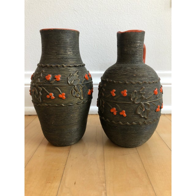 Pair of Mid Century pottery vessels with a metallic striated glaze and floral motif. Burnt orange accents in the floral...