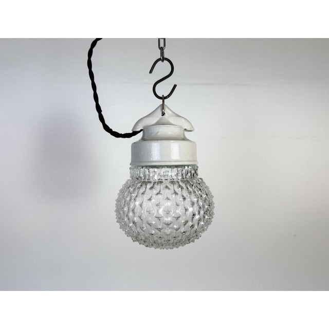 Vintage industrial light made in former Czechoslovakia during the 1970s. It features a white porcelain top and a glass...