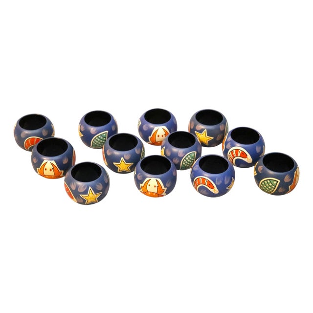 A set of twelve wooden napkin rings. Hand painted with whimsical coastal inspired characters including a crab, a star, a...