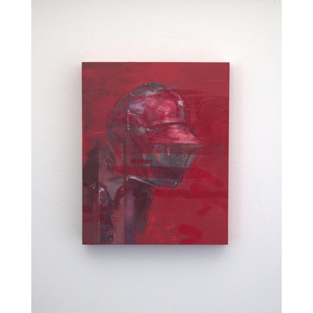 The artwork features a striking depiction of a helmet, rendered in deep reds and subtle metallic tones that create a sense...
