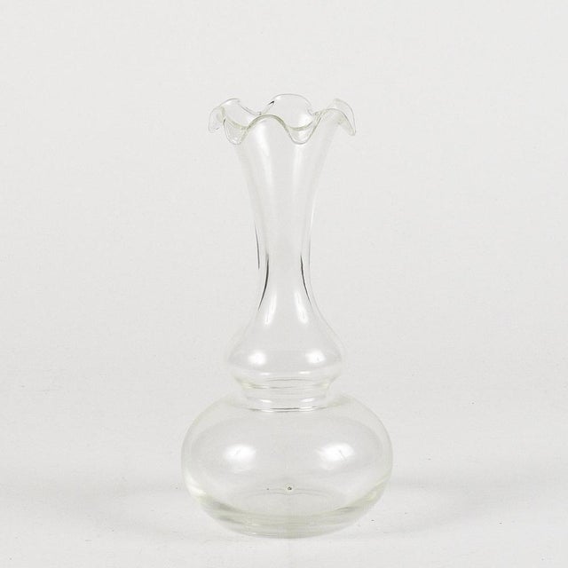 Transparent 20th century hand-blown glass vase with soft lines and a narrow neck with a movement on the edge. Measures 12...