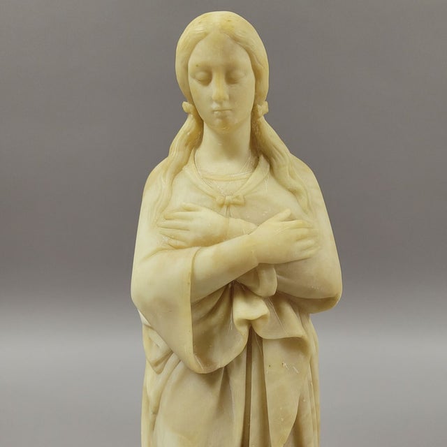 Alabaster statue of girl standing on snake. This might be the Virgin Mary in the Garden of Eden and stepping on the snake...