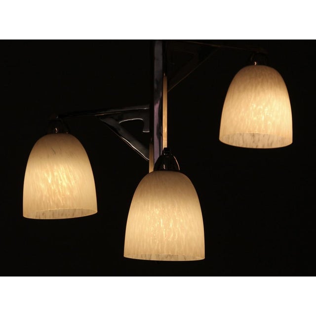 This original Art Deco chandelier consists of three arms at different heights, each featuring a white pate de verre tulip....