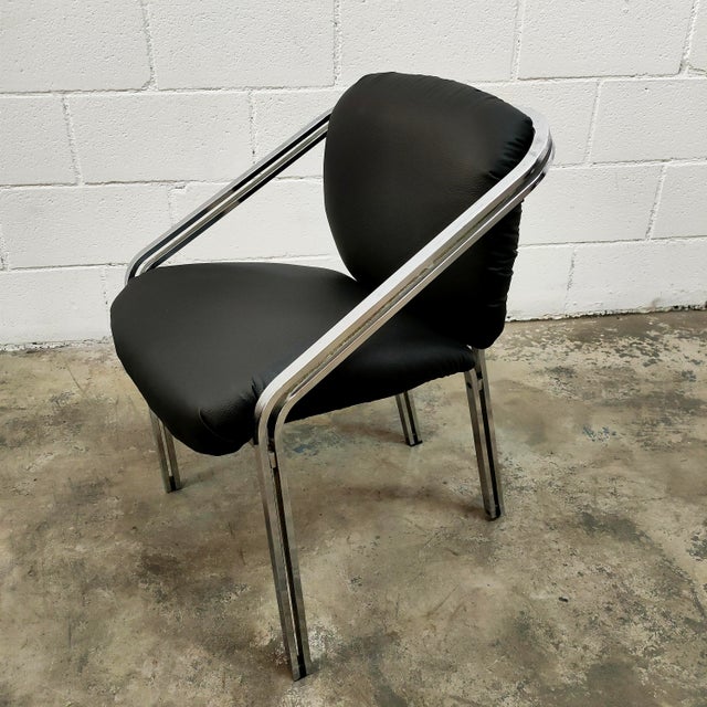 Armchairs with a chromed steel frame and black faux leather upholstery. This mid-century modern piece was manufactured in...