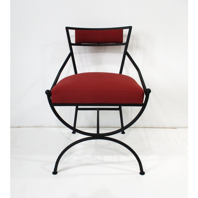 A set of four sculptural satin black iron dining chairs upholstered in a Sunbrella fabric so they can be used outdoors or...