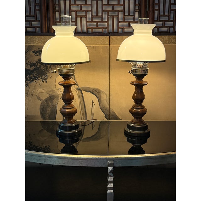 Design Plus Gallery presents a Pair of Vintage Oil-Lamp Style Table Lamps. Each lamp has a turned wood column with carved...