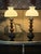 Design Plus Gallery presents a Pair of Vintage Oil-Lamp Style Table Lamps. Each lamp has a turned wood column with carved...