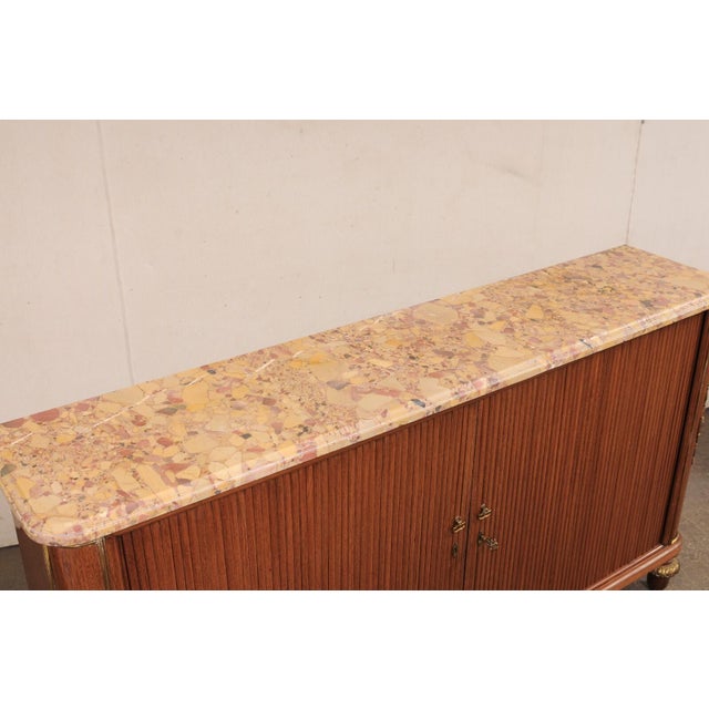 A French console chest with tambour doors and its original marble top, from the early 20th century. This antique chest...