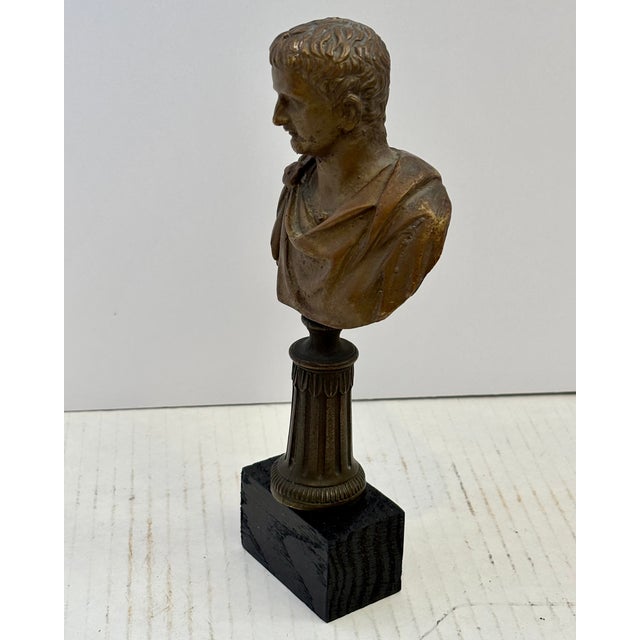 Bronze Bust of the Roman Emperor Tiberius, mounted on a fluted pedestal a a square wooden base, characterized by its...