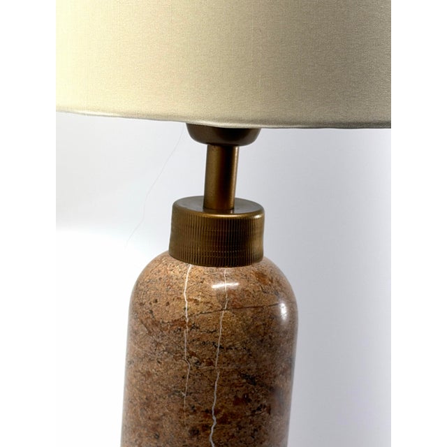 A substantial pink marble table lamp featuring dramatic natural veining and finely ribbed antiqued brass details. The...
