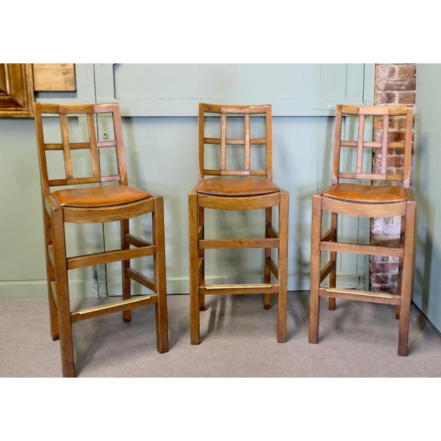 A trio of early 20th century oak lattice back dining chairs, probably by Heals, the chairs are in Golden Oak. They have...