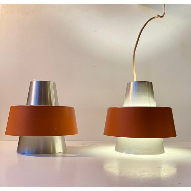 A rare set of hanging ceiling lamps in earthy orange and brushed aluminum. This model was made at nordisk solar compagni...