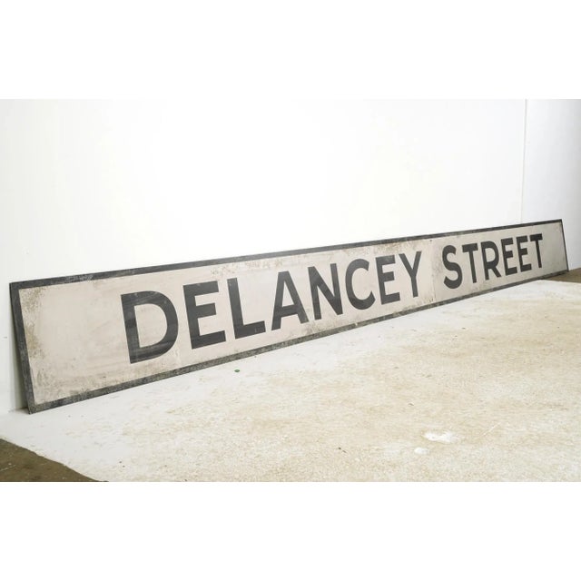 Reclaimed movie set street sign made of plastic foam board in white and black colors. The sign reads "Delancey Street"....