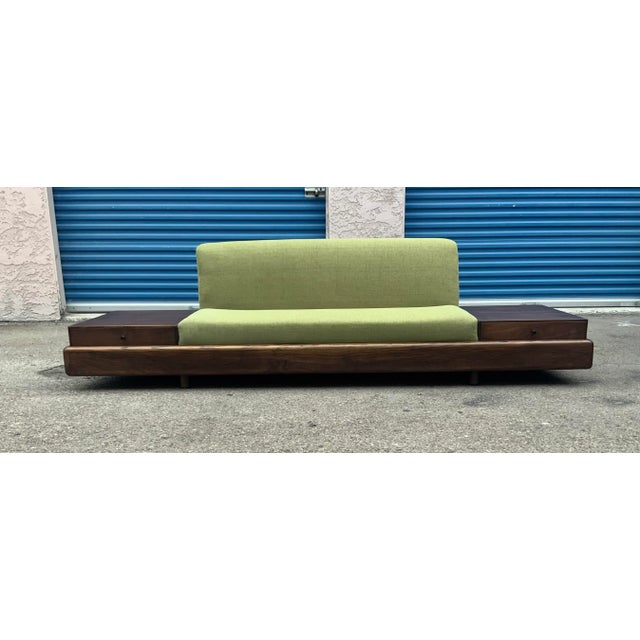 Walnut platform sofa in the manner of Adrian Pearsall. Sofa is made of solid walnut. Has 2 drawers. The sofa was newly...