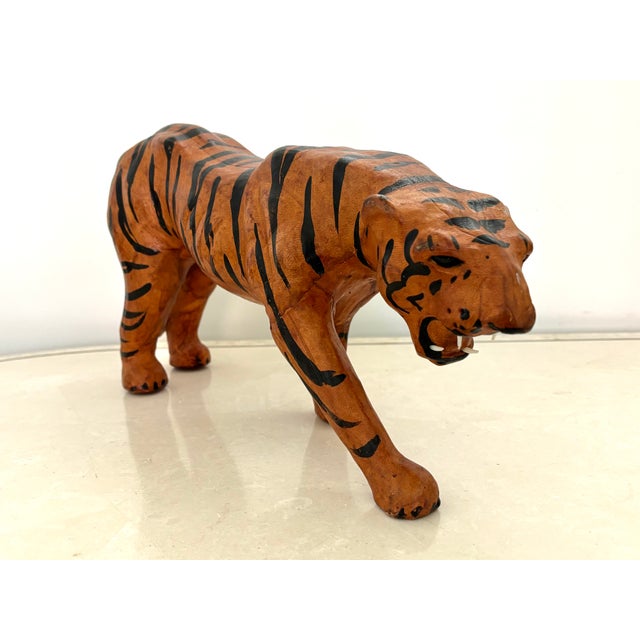 A leather sculpted tiger statue, from India c.1970. The solid body is finished in an aged leather. The tiger has glass...