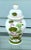 Vintage Lotus Ginger Jar with Gilded Finial Features a hand-painted lotus blossom motif in soft blush, sage, and verdant...